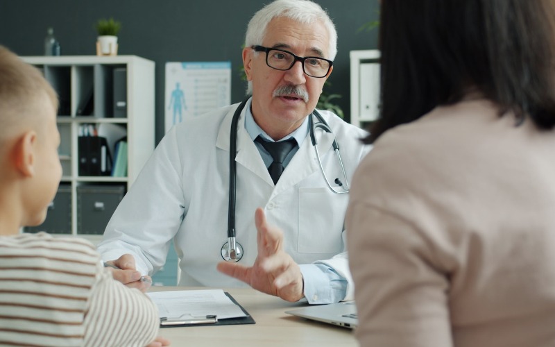Doctor consults with mother and child in office.